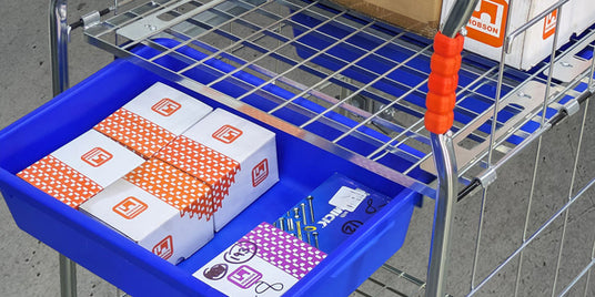 Cart with blue tray containing boxes and a red handle on a tiled floor.