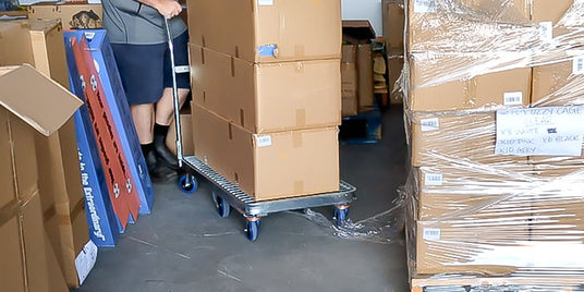 Person pushing a trolley with boxes in a warehouse setting