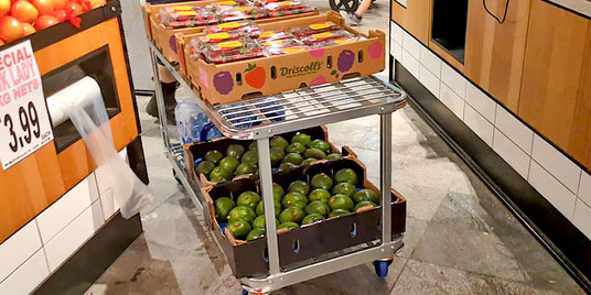 trolley with green apples and oranges in a grocery store setting