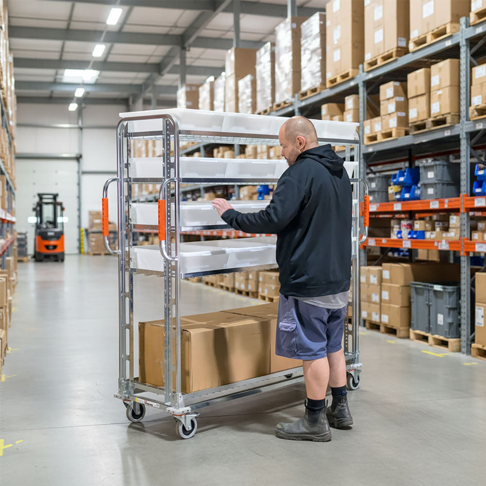 a warehouse worker loading a large jumbo parts trolley with 5 adjustable shelves and totes