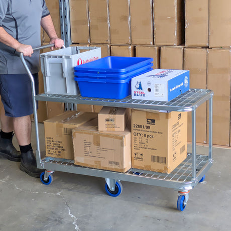 worker pushing 62 tier trolley in warehouse loaded with totes and cartons